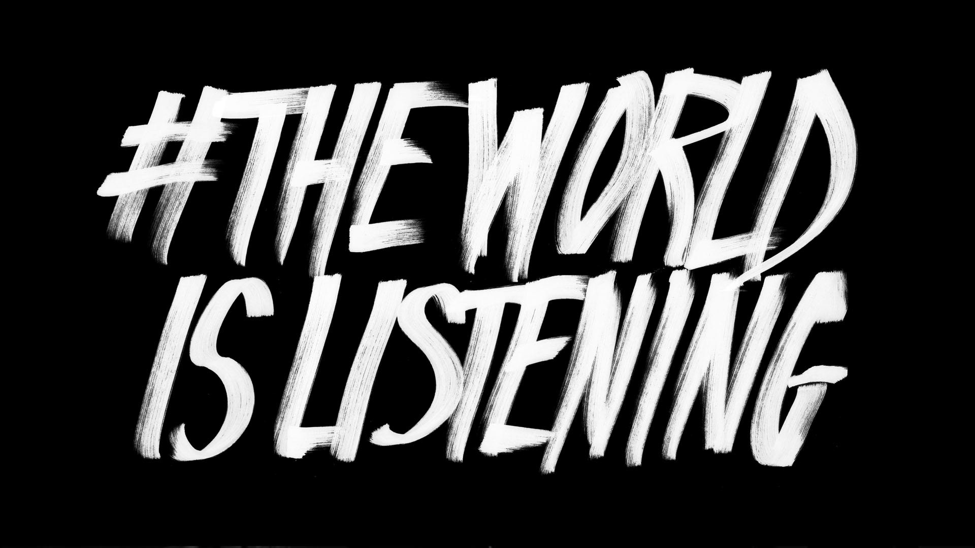 Black background with bold, white, handwritten text reading "#THEWORLD IS LISTENING". The letters are slightly uneven, giving a dynamic, urgent feel to the message. .