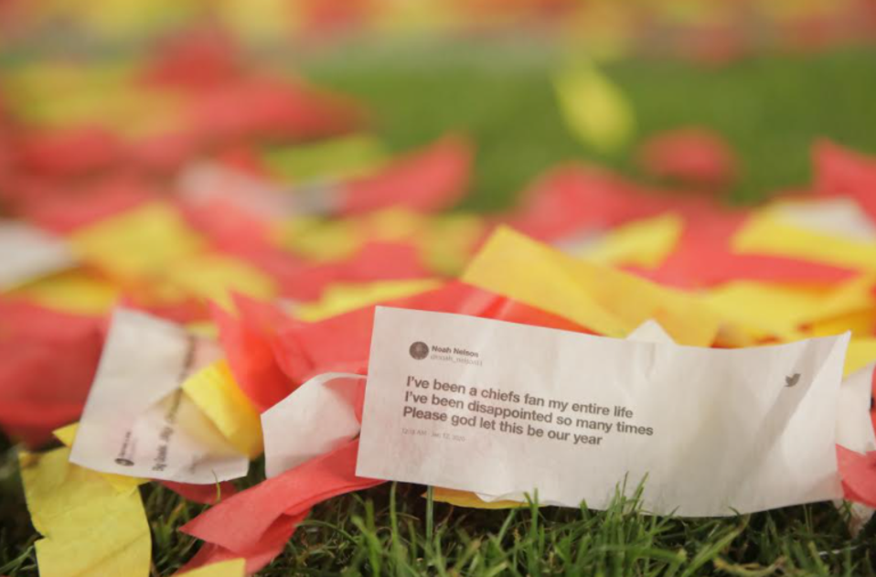 A crumpled tweet on a piece of paper lies amidst red and yellow confetti on grass. The tweet reads, "I've been a Chiefs fan my entire life. I've been disappointed so many times. Please god let this be our year.