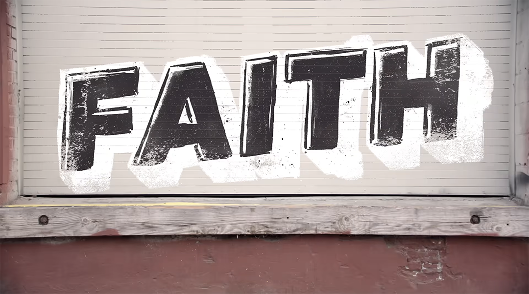A mural on a wall depicts the word "FAITH" in large, bold, black and white graffiti-style letters. The letters have a textured, weathered appearance, and the mural is set against a corrugated metal backdrop with a wooden and brick base below.